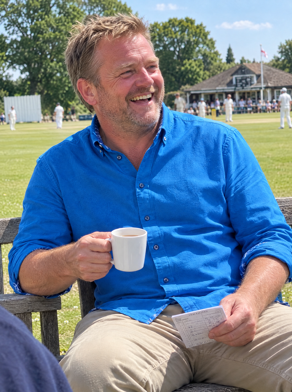 Man wearing the Cobalt Blue Oxford button-down shirt at a village cricket match