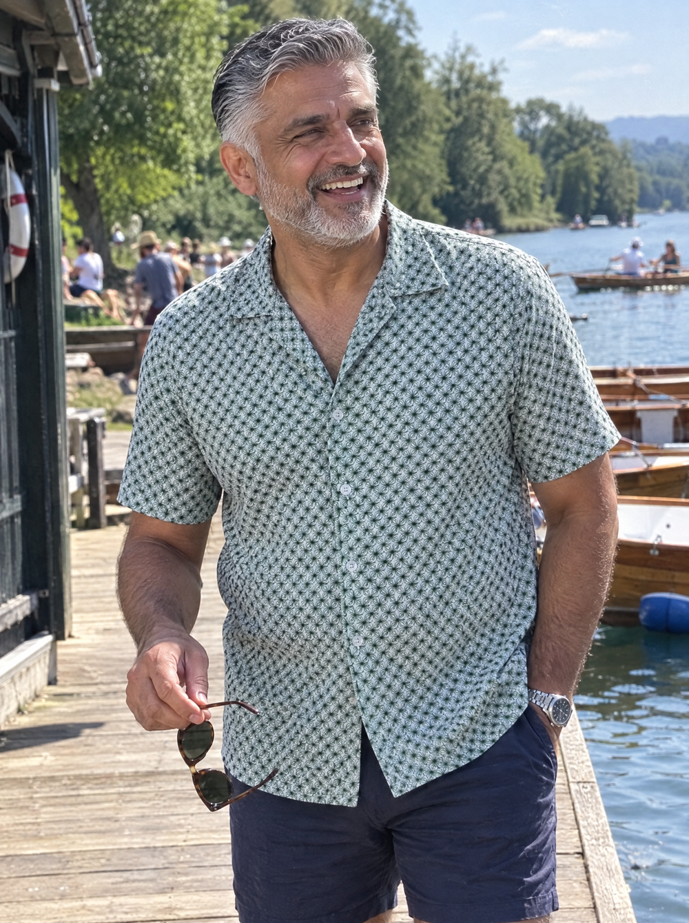 Man wearing the Emerald Wavy Geo Open Collar shirt at a lakeside boathouse