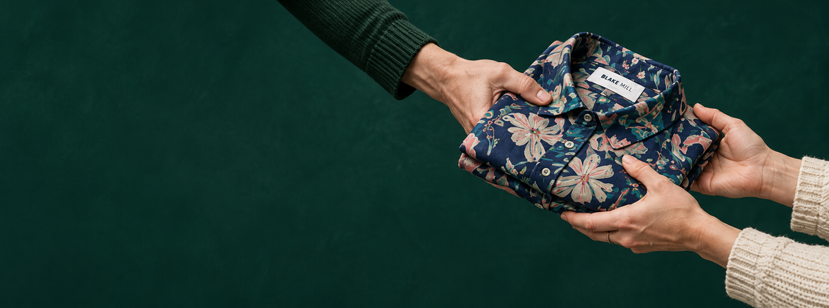 A folded floral shirt being passed from one person to another