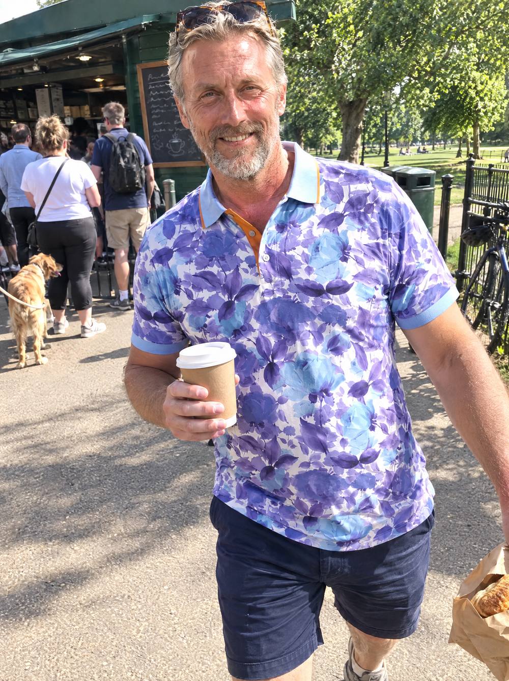 Man wearing the Summer Breeze Printed Polo at a park coffee kiosk